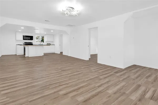 an empty room with wooden floor and chandelier