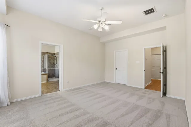 a view of an empty room with a chandelier fan
