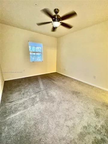 an empty room with a ceiling fan and carpet