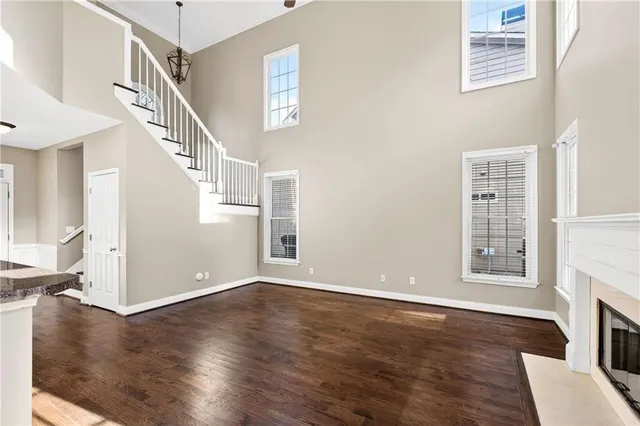 an empty room with wooden floor fireplace and windows