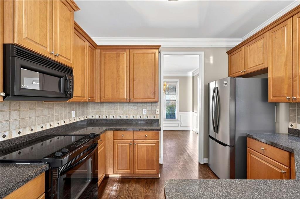 5731 Vinings Retreat Way Southwest Mableton, GA 30126 - Photo 7 of 32 a kitchen with granite countertop a refrigerator stove and microwave
