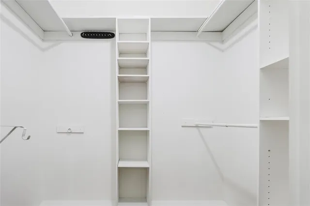 a view of walk in closet with empty racks