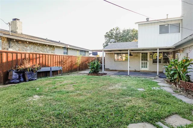 a backyard of a house with potted plants and large tree