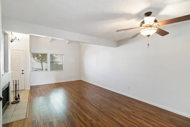 an empty room with wooden floor fan and windows