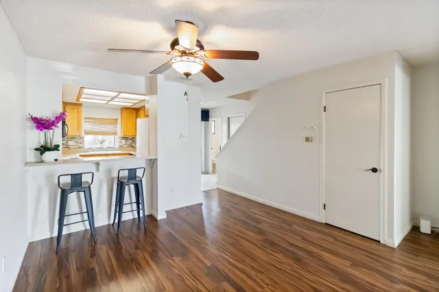 a view of a dining room with wooden floor chandelier a flat screen tv and a kitchen view
