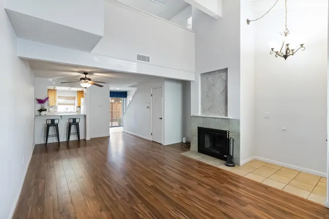 an empty room with wooden floor fireplace and windows