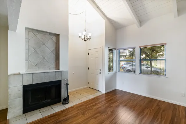 an empty room with wooden floor fireplace and windows