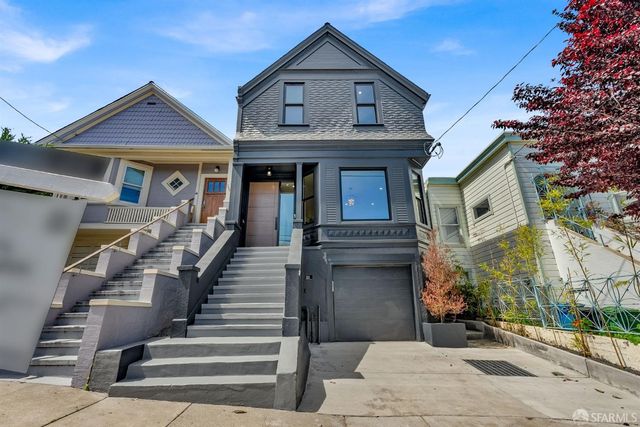 a view of a white house with large windows and a small yard