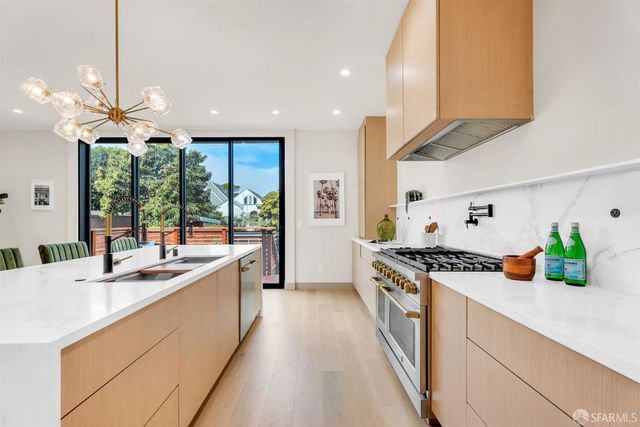 a kitchen with a stove a sink a counter top space and living room view