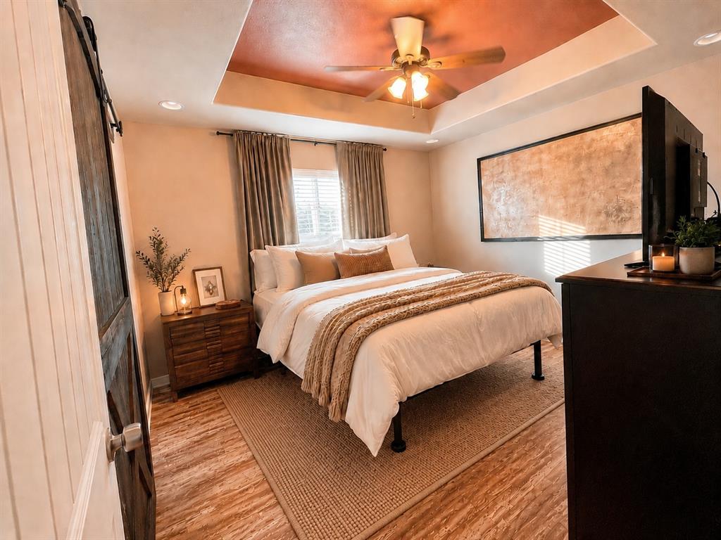 420 Sessums Road Springtown, TX 76082 - Photo 17 of 40 Recessed tray ceiling with a ceiling fan, wood-finish flooring, and a sliding barn door-virtually staged