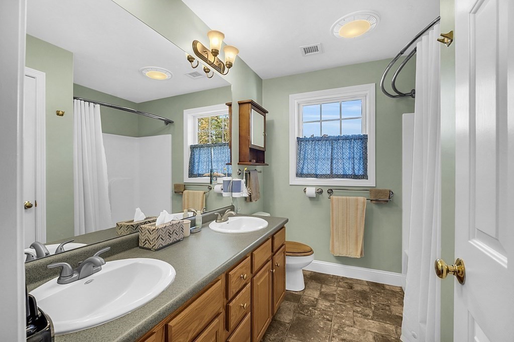 79 River Road Pepperell, MA 01463 - Photo 14 of 30 a bathroom with a granite countertop sink toilet a mirror a vanity and shower