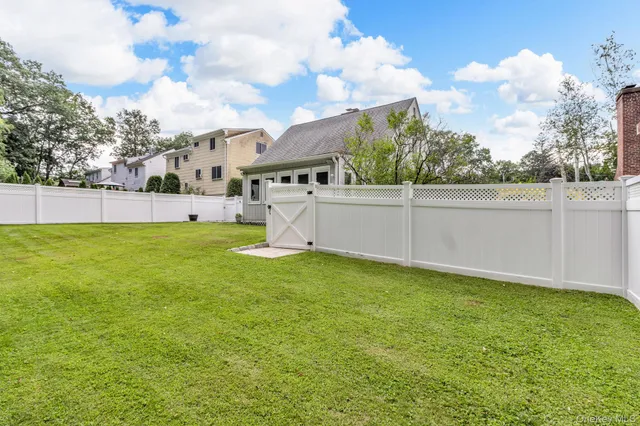 a view of a backyard with table and chairs plants and large tree