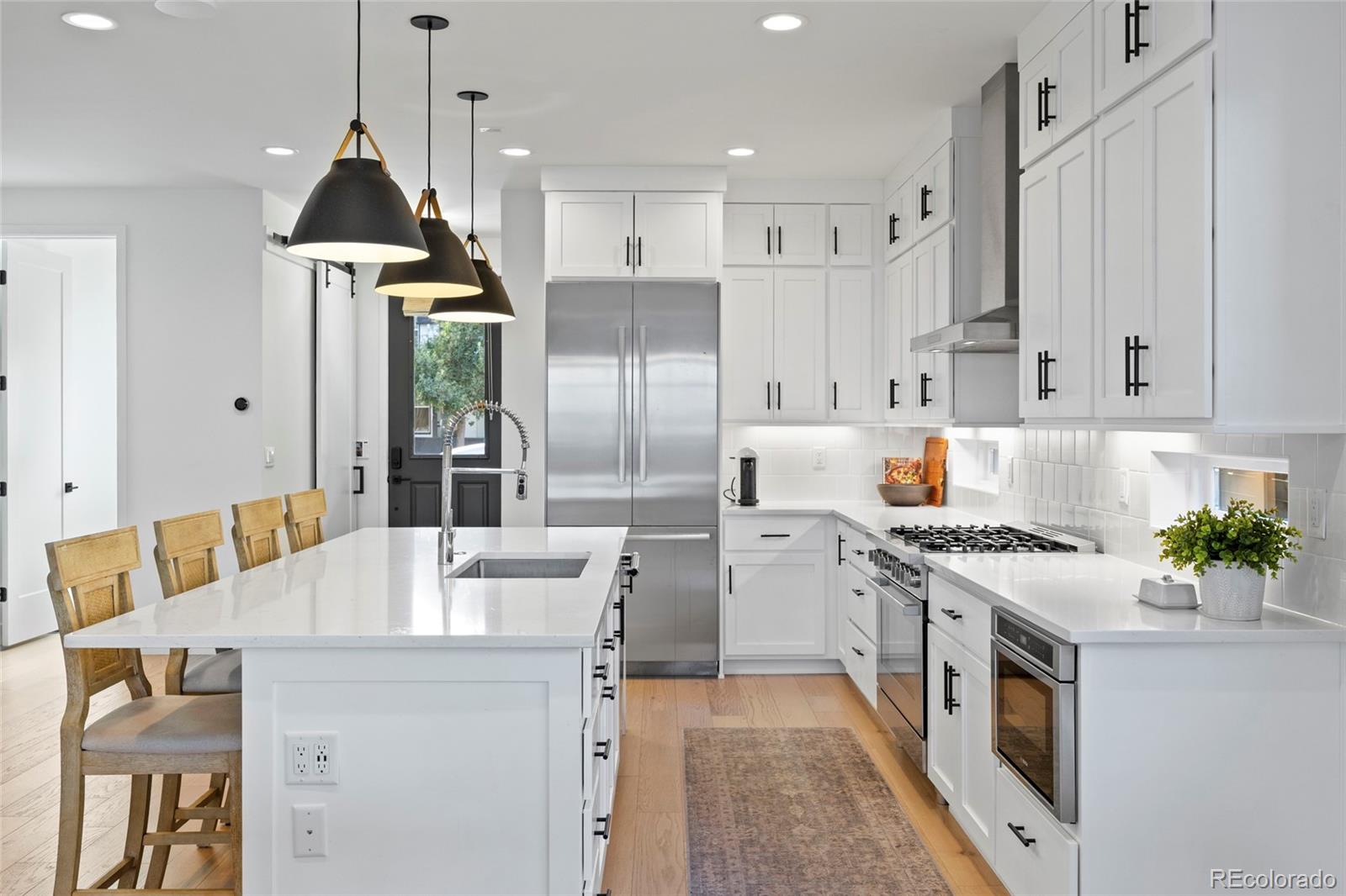 3922 Osage Street Denver, CO 80211 - Photo 6 of 44 a kitchen with stainless steel appliances a stove a sink a refrigerator a center island and chairs