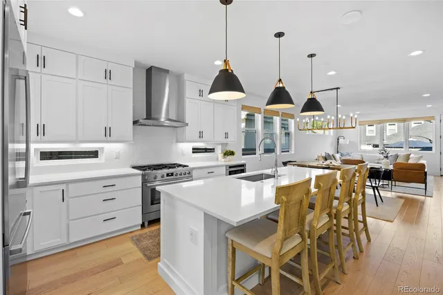a kitchen with stainless steel appliances kitchen island granite countertop a sink a stove and a wooden floor
