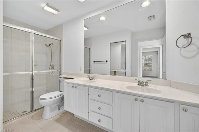 a bathroom with a double vanity sink toilet mirror and shower