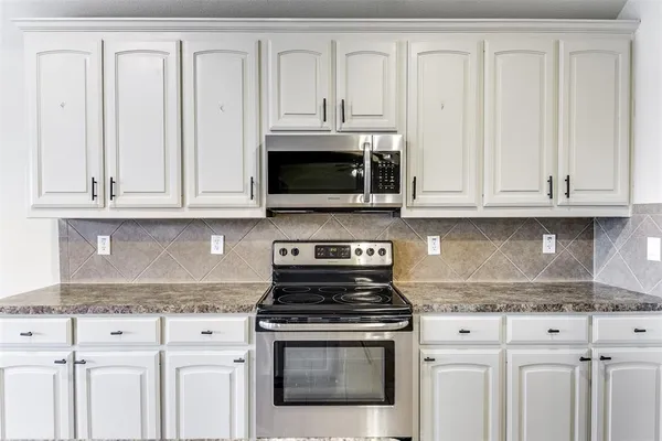 a kitchen with granite countertop white cabinets and stainless steel appliances