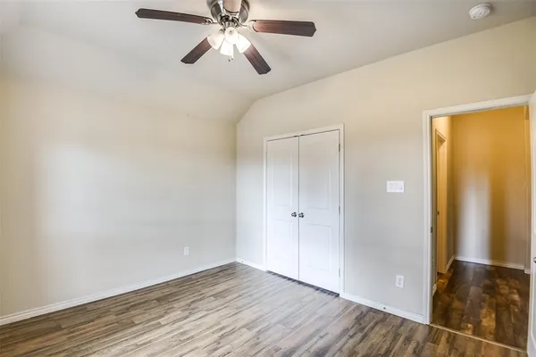 an empty room with wooden floor closet and windows