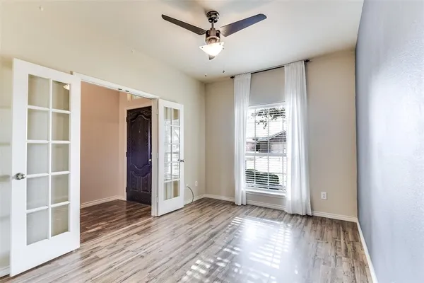 a view of an empty room with wooden floor and a window