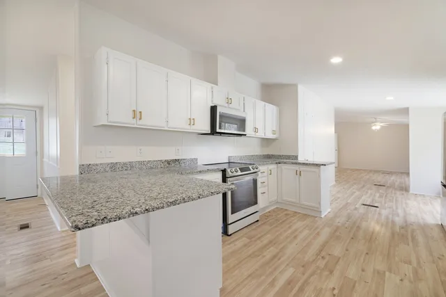 a kitchen with granite countertop white cabinets and white appliances