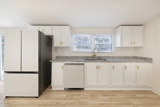 a kitchen with granite countertop a refrigerator sink and cabinets