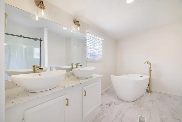 a spacious bathroom with a double vanity sink a mirror and a bathtub