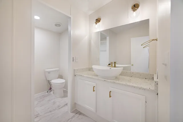 a bathroom with a granite countertop sink a toilet and a mirror