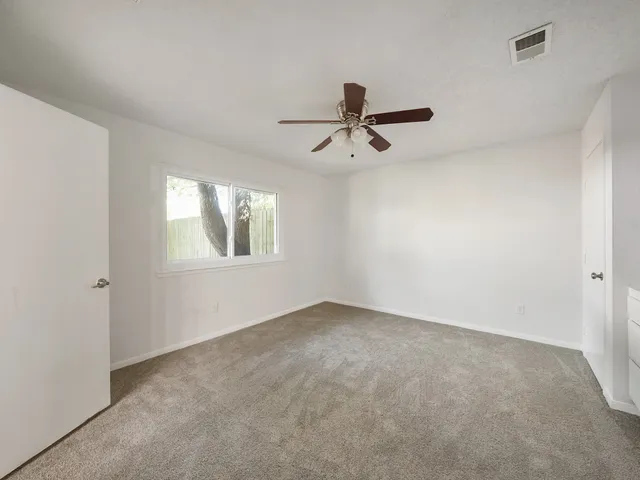 an empty room with a window and a fan