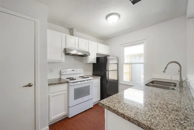 a kitchen with kitchen island granite countertop a stove and a sink