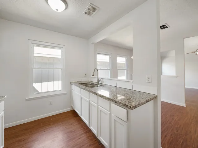 a kitchen with granite countertop a sink and dishwasher with wooden floor