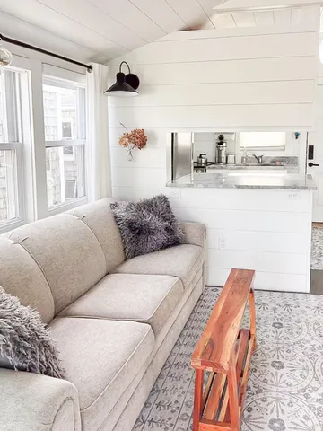 a living room with furniture a flat screen tv and a large window