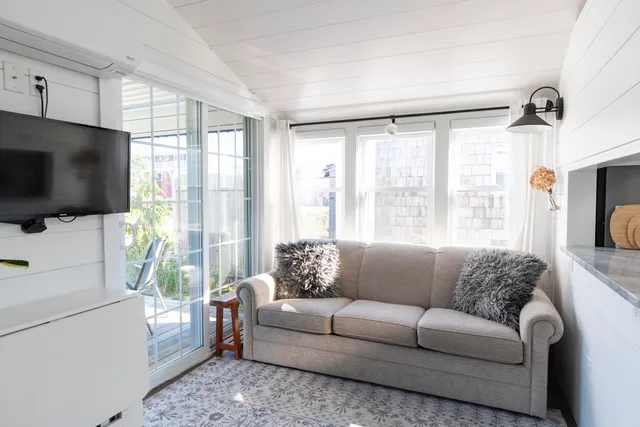 a living room with furniture a flat screen tv and a large window