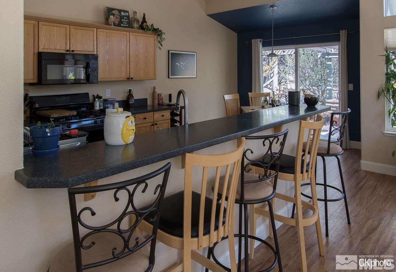9760 Frankwood Drive Reno, NV 89521 - Photo 11 of 24 a kitchen with stainless steel appliances granite countertop a stove top oven a sink a dining table and chairs with wooden floor