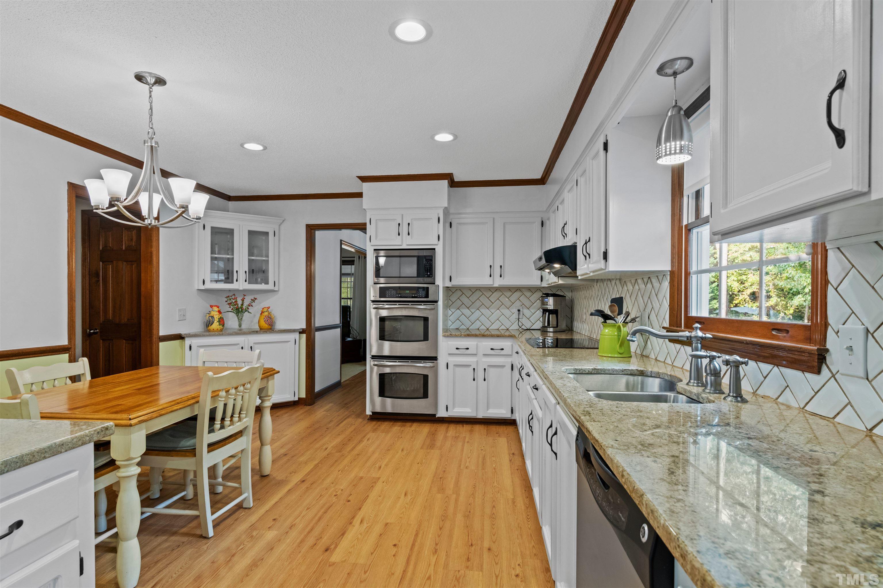8417 Crowder Road Raleigh, NC 27603 - Photo 14 of 30 a kitchen with stainless steel appliances granite countertop a refrigerator a sink dishwasher a stove and white cabinets with wooden floor