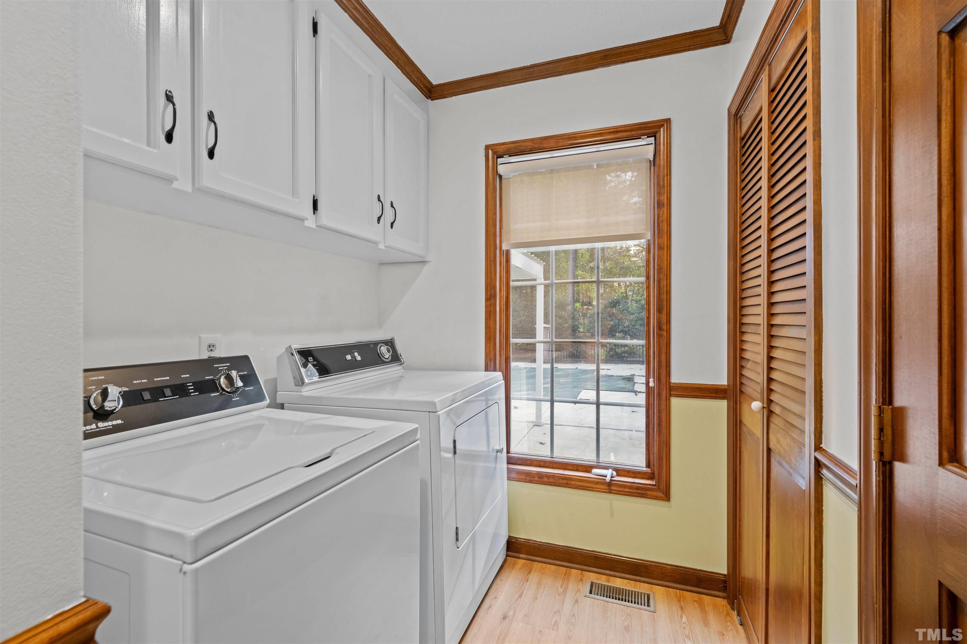 8417 Crowder Road Raleigh, NC 27603 - Photo 19 of 30 a view of washer and dryer with white cabinets