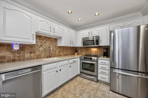 a kitchen with stainless steel appliances granite countertop a refrigerator sink and stove
