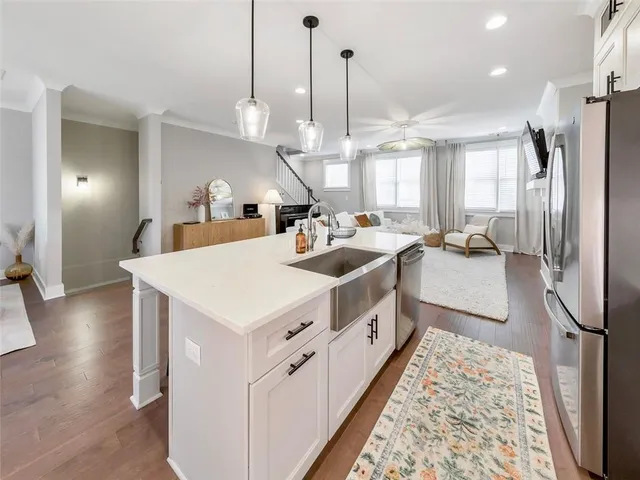 a large white kitchen with a large window a sink a center island and stainless steel appliances