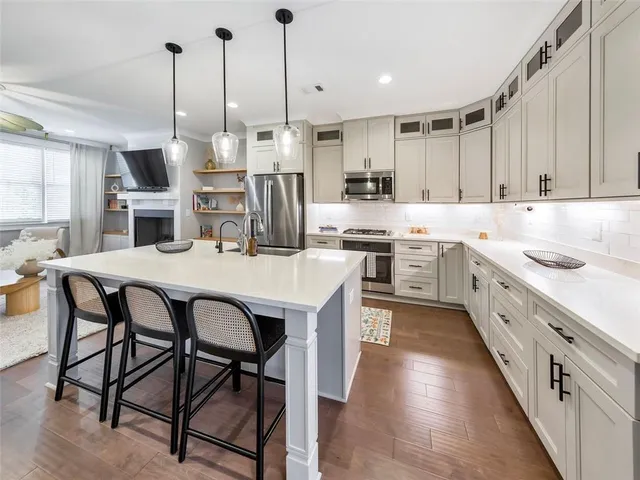 a kitchen with stainless steel appliances kitchen island granite countertop a table chairs sink and cabinets