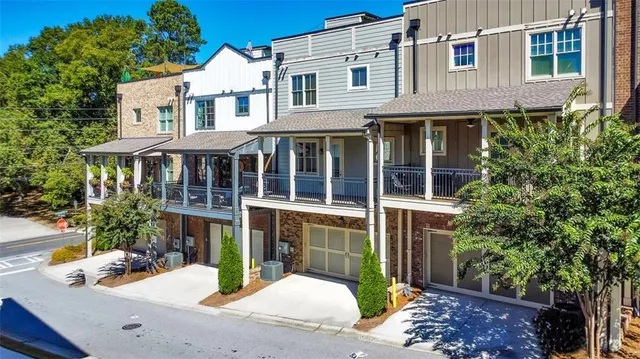 a view of a brick house with plants and large tree