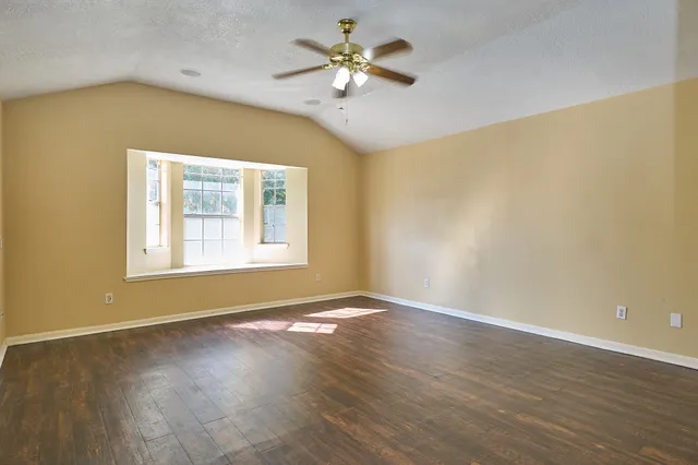 a view of an empty room with window and wooden floor