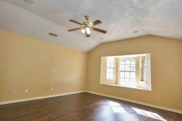 a view of an empty room with chandelier fan and a window