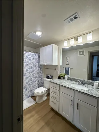 a bathroom with a granite countertop sink toilet and mirror
