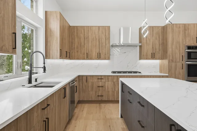 a large kitchen with a large counter top a sink stainless steel appliances and cabinets