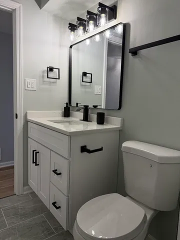 a bathroom with a toilet sink vanity tub and mirror