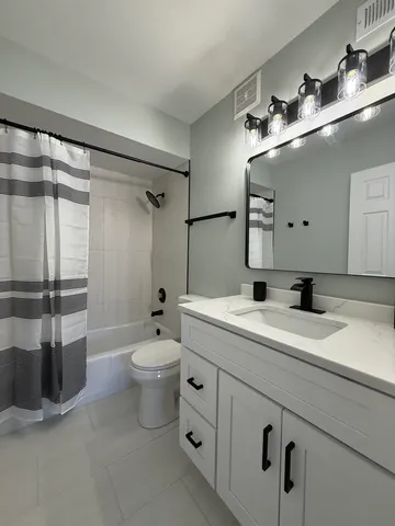 a bathroom with a double vanity sink toilet mirror and shower