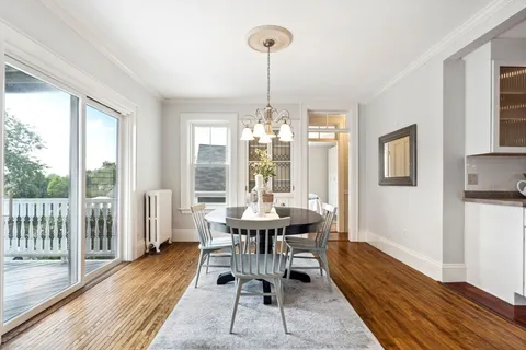 a dining room with wooden floor a chandelier a wooden table and chairs