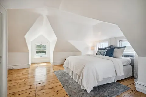 a spacious bedroom with a bed and wooden floor