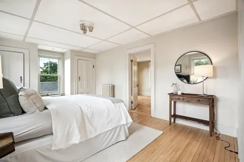 a bedroom with a bed a mirror and painting on the wall