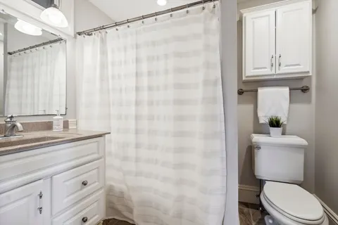 a bathroom with a granite countertop sink a toilet and a shower