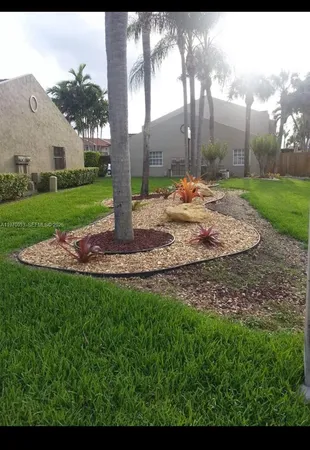 a view of a fountain in front of a brick house with a big yard