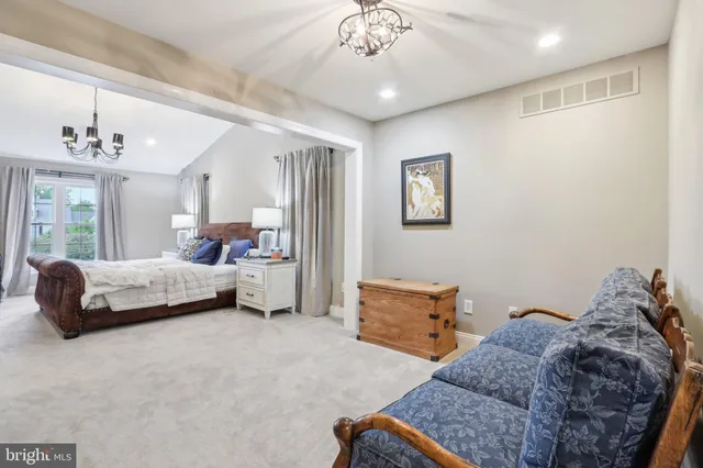 a spacious bedroom with a bed a couch and a chandelier